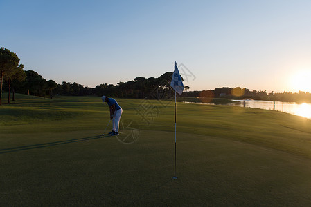 高尔夫球手与司机美丽的日落球场击球图片