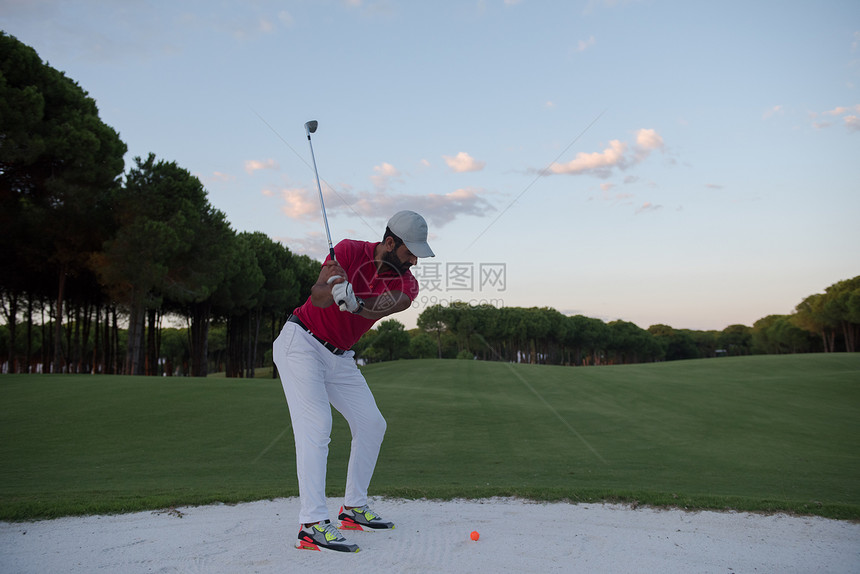 高尔夫球手球场上用美丽的日落太阳耀斑沙坑射球图片