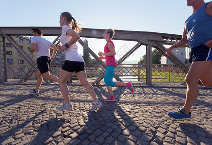 人们分慢跑跑步者队早晨训练锻炼与日出背景图片