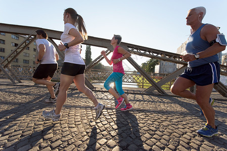 人们分慢跑跑步者队早晨训练锻炼与日出背景图片