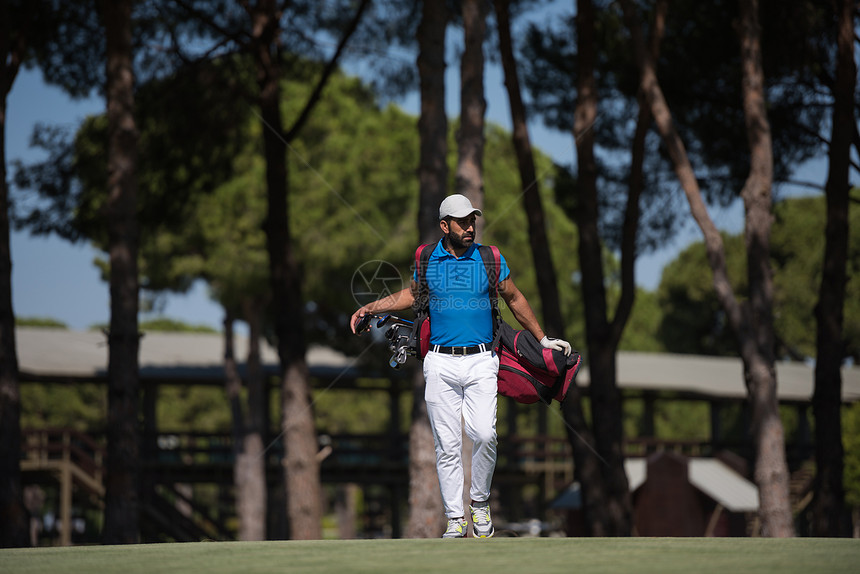 英俊的中东高尔夫球员背着包,球场上走下个洞图片