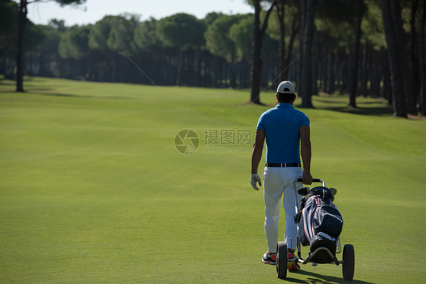 美丽的阳光明媚的天,英俊的中东高尔夫球员带着车轮袋球场上行走图片