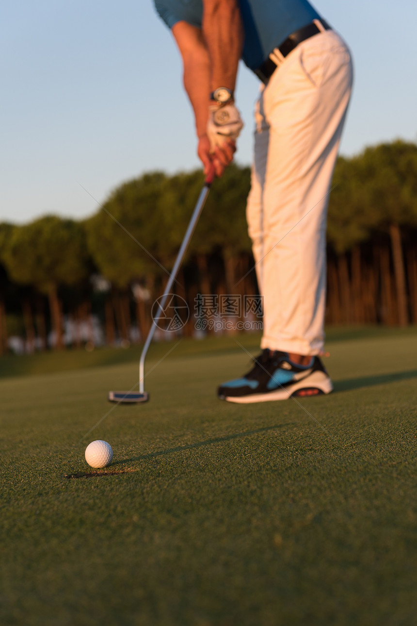 高尔夫球手击球与司机高尔夫球场美丽的日落背景图片