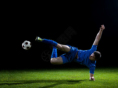 足球运动员足球场上踢球,黑色背景上被隔离高清图片