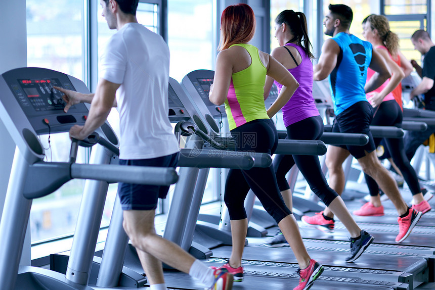 群轻人现代体育健身房的跑步机上跑步图片