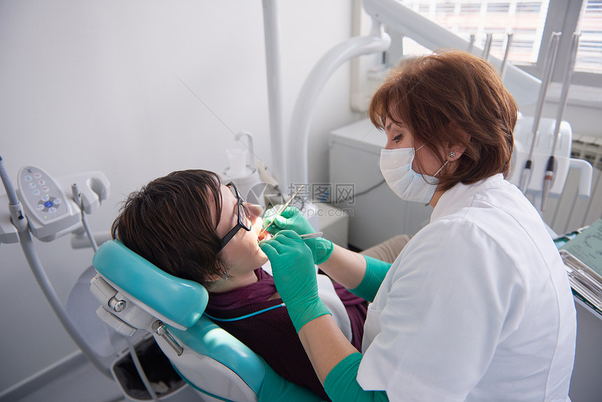 名妇女病人牙医的特写镜头,等待与背景中的女医生进行检查图片