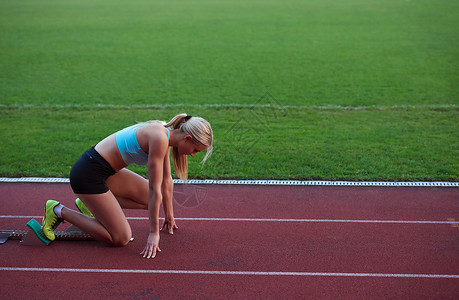 运动员女子体足球场上的田径跑道上跑步,代表体育中的竞争领导理念图片
