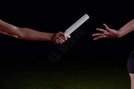 女子运动员接力赛中传递接力棒背景图片