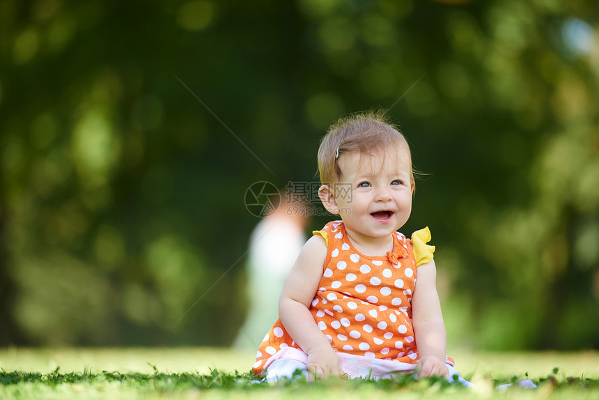 快乐的幼儿坐草地上,美丽的夏天公园里图片