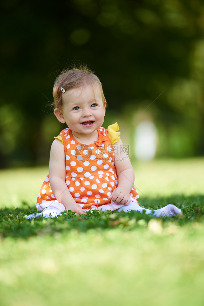 快乐的幼儿坐草地上,美丽的夏天公园里图片