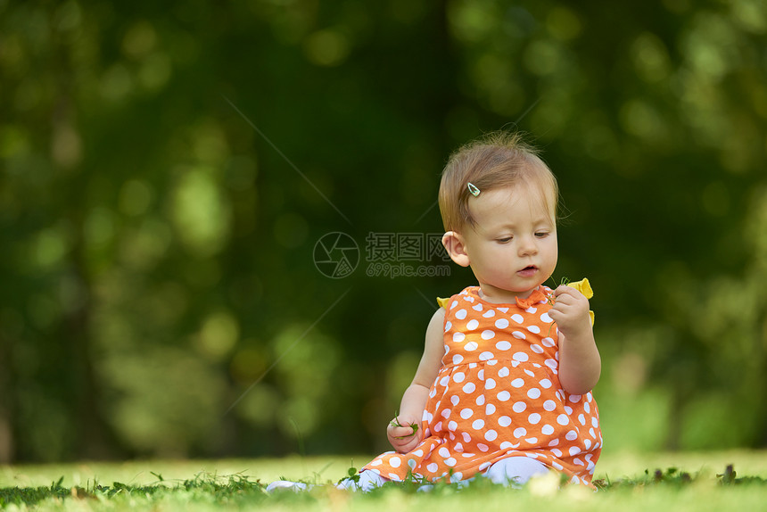 快乐的幼儿坐草地上,美丽的夏天公园里图片