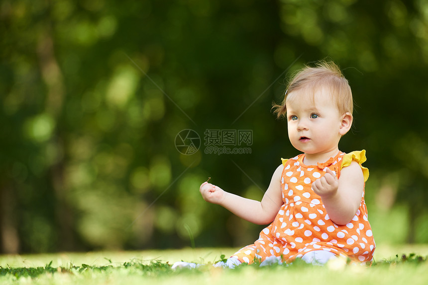 快乐的幼儿坐草地上,美丽的夏天公园里图片