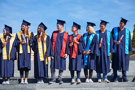 毕业日,轻的毕业生们站大学大楼前高清图片