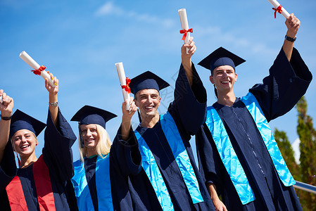 毕业日,轻的毕业生们站大学大楼前图片