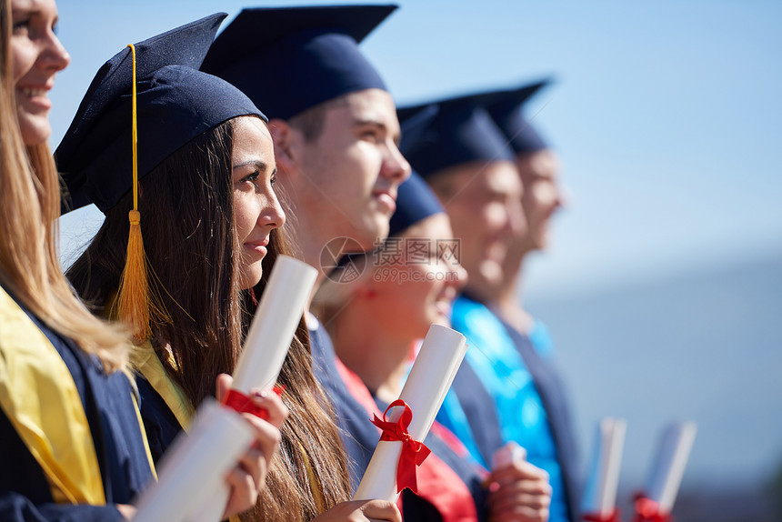 毕业日,轻的毕业生们站大学大楼前图片