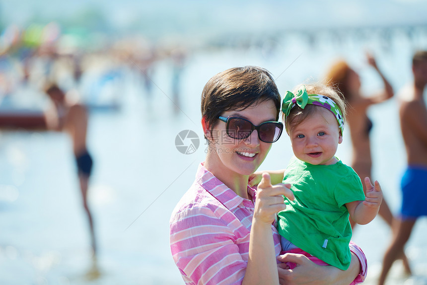 快乐的妈妈宝宝海滩上玩得开心,同时学会走路迈出步图片