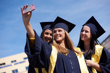 毕业生照片捕捉个快乐的时刻学生们聚集大学毕业生穿着毕业礼服,拍自拍照片背景