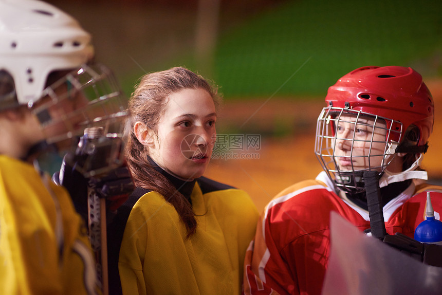 轻的青少,女孩冰球运动员队会议与教练室内体育竞技场图片