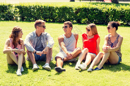夏天人的群微笑的朋友户外坐公园的草地上图片
