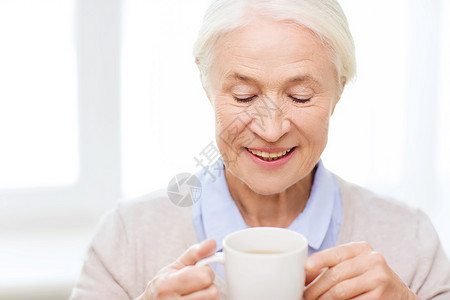 龄,饮料人的快乐的微笑老妇女家里喝杯茶咖啡图片