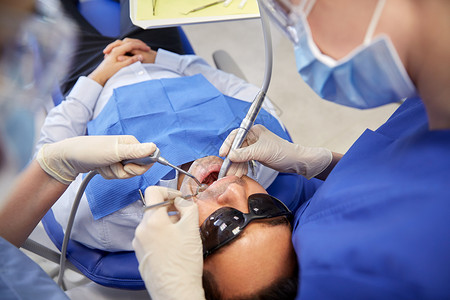 人,医学,口腔医学保健女牙医助理牙科镜,钻空气水喷雾治疗男病人牙齿牙科诊所图片