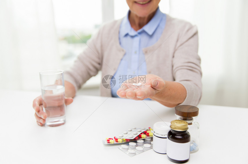 龄,医学,保健人的亲密的快乐老妇女与药丸璃水家里图片