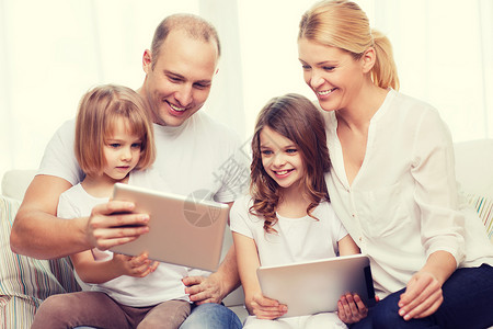 家庭,孩子,技术,金钱家庭微笑的家庭两个小女孩家里平板电脑电脑图片