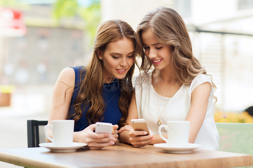 技术生活方式友谊人的快乐的轻妇女十几岁的女孩户外咖啡馆用智能手机咖啡杯图片