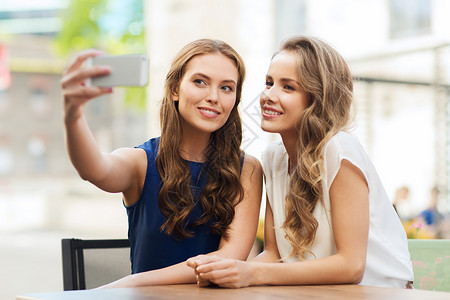技术,生活方式,友谊人的快乐的轻妇女十几岁的女孩用智能手机户外咖啡馆自拍图片