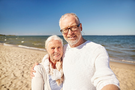龄,旅游,技术人的快乐的老夫妇拍照与智能手机自拍杆夏季海滩图片