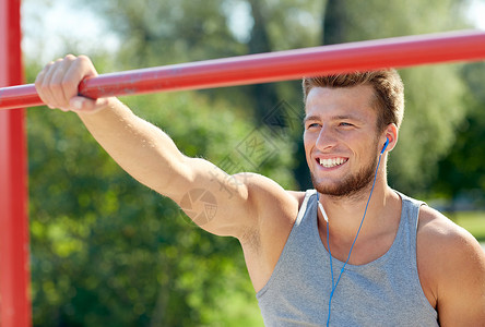 健身,运动,训练生活方式的快乐的轻人带着耳机听音乐,户外的水平酒吧锻炼图片