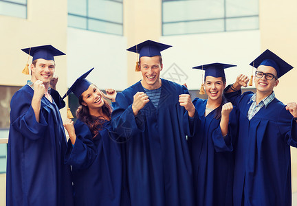 教育,毕业人的群微笑的学生穿着沙黑板长袍户外胜利的手势图片