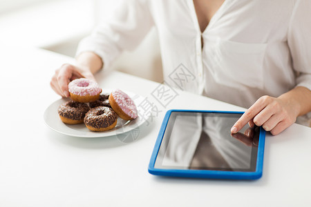 人,垃圾食品,饮食,技术健康的饮食用平板电脑甜甜圈数卡路里,坐家里的桌子上图片
