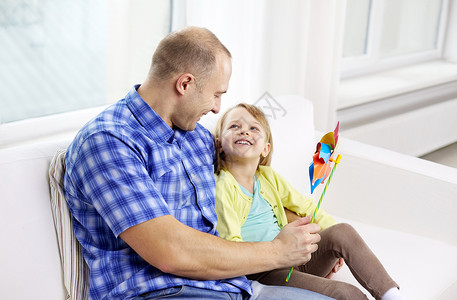 家庭,孩子,父亲日为人父母的快乐的父亲女儿坐家里的沙发上图片