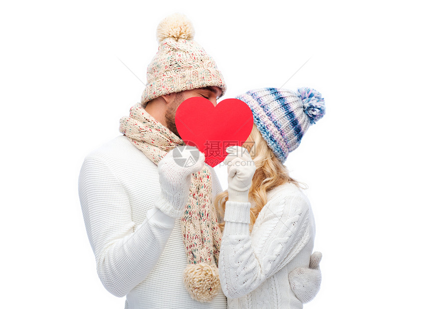 爱情,情人节,情侣,诞节人的微笑的男人女人戴着冬帽围巾,躲红色的纸心形后图片
