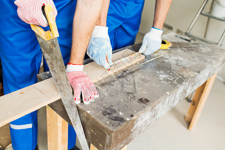 建筑,木工,修理,队合作人的建筑工人与手臂锯锯板桌子上图片
