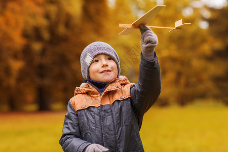 童梦飞扬秋天,童,梦想,休闲人们的快乐的小男孩户外玩木制玩具飞机背景