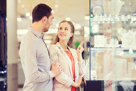 销售,消费主义人们的幸福的夫妇指着购物窗口商场的珠宝店图片