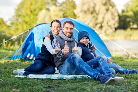 露营,旅游,徒步旅行人们的快乐的家庭帐篷营地展示竖大拇指的手势图片