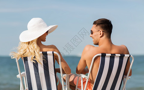 海滩晒太阳人爱情,旅行,旅游,夏天人的微笑的夫妇度假穿着泳装坐椅子上,后海滩上晒太阳背景