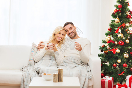 家庭,诞节,假日,爱人的幸福的夫妇覆盖着格子喝茶,坐家里的沙发上图片