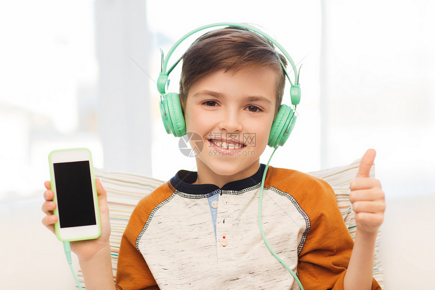 休闲,孩子,技术,手势人的微笑的男孩与智能手机耳机听音乐,并大拇指家里图片
