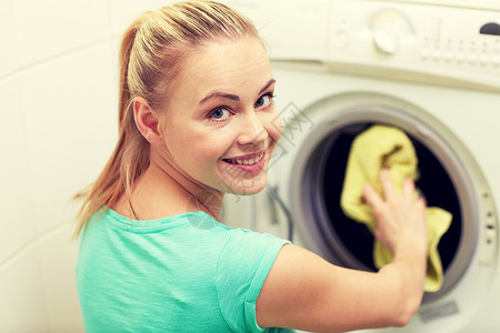 人,家务,洗衣家务快乐的女人家里把衣服放进洗衣机图片