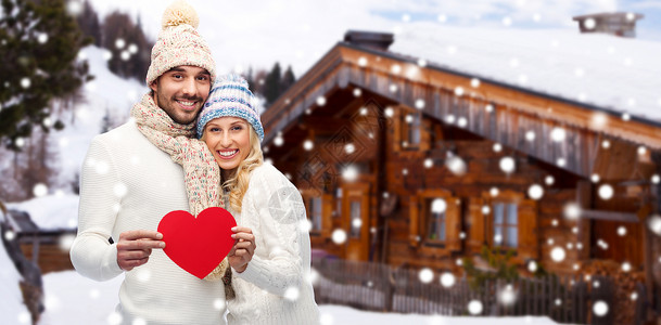 隔空拥抱爱情,情人节,情侣,诞节人的微笑的男人女人戴着冬天的帽子围巾,木屋雪背景上着红色的纸心形背景