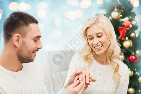 爱情,诞节,情侣,求婚人的快乐的男人蓝色假日灯光背景下给女人钻石订婚戒指图片