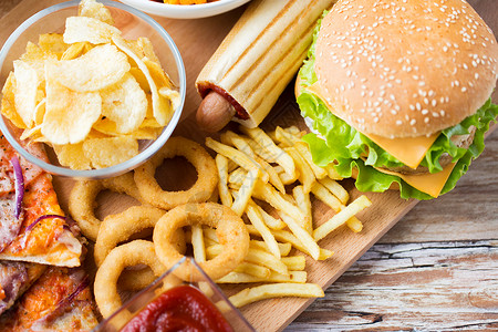 快餐健康的饮食汉堡奶酪汉堡,油炸鱿鱼戒指,炸薯条热狗薯片木制桌视图图片