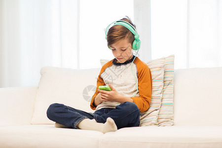 休闲,儿童,技术人的男孩与智能手机耳机听音乐家里玩游戏图片