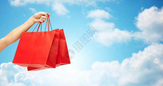 人,销售,消费主义,广告商业近距离手红色空白购物袋蓝天云彩的背景图片