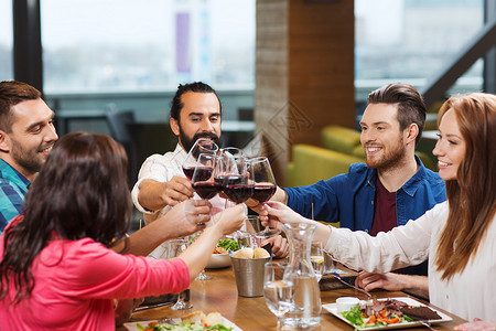 休闲,庆祝,食物饮料,人假日的微笑的朋友餐厅吃晚餐喝红酒图片