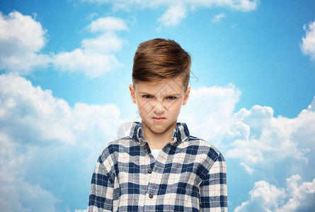 蓝色格子衬衫童,情感,愤怒,仇恨人的愤怒的男孩穿着格子衬衫蓝天云彩的背景上背景